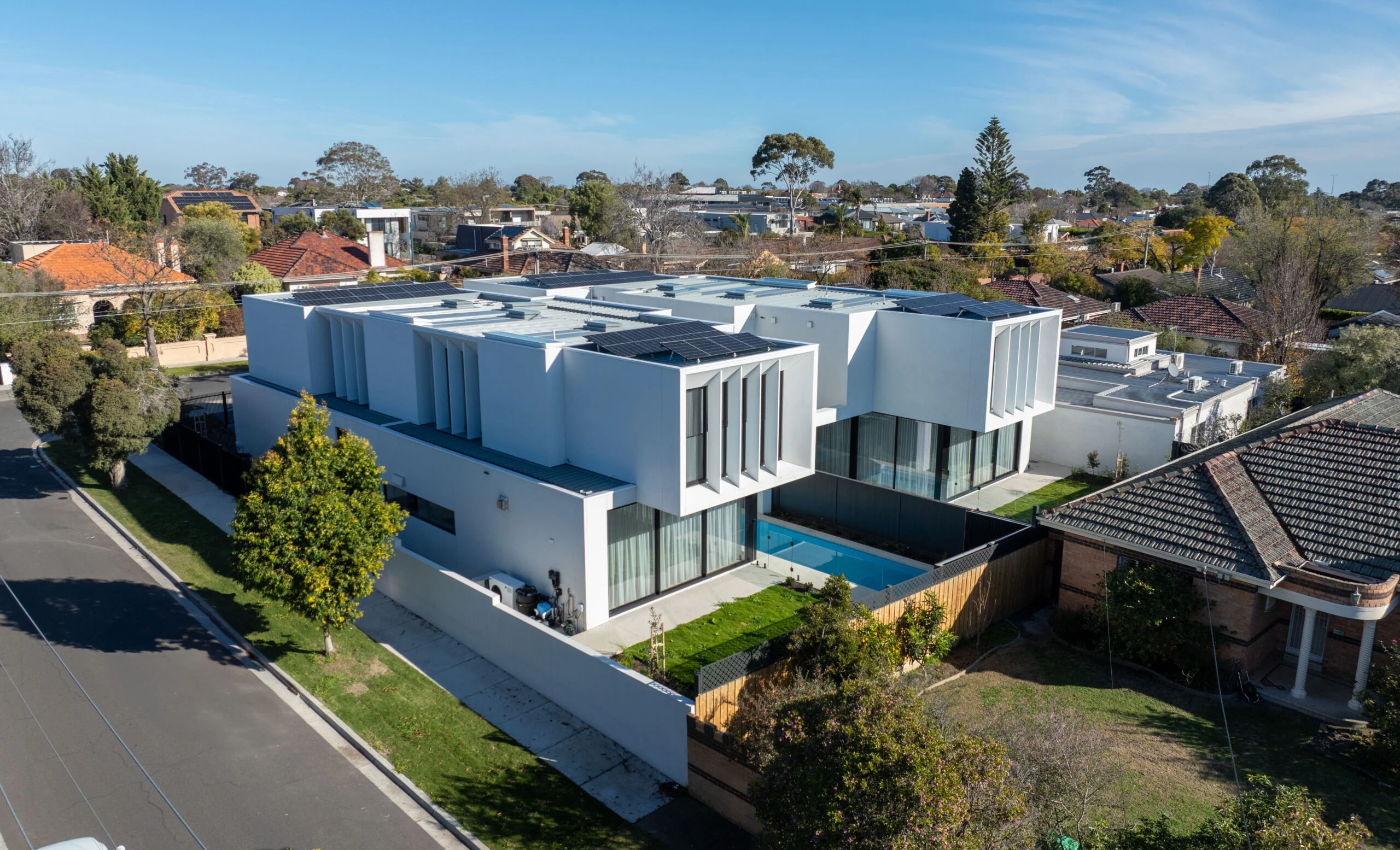 Aerial view of a completed modern white home with a pool